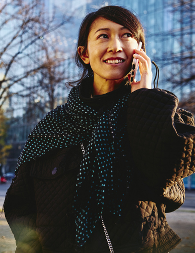 Smiling woman on the phone, office buildings on background.