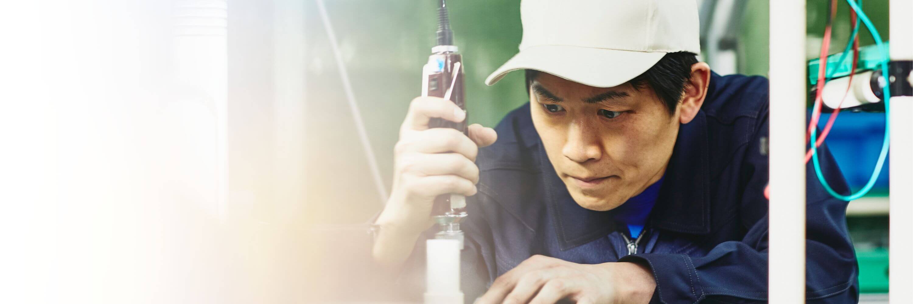 Man wearing a white hat working with tools on a production site
