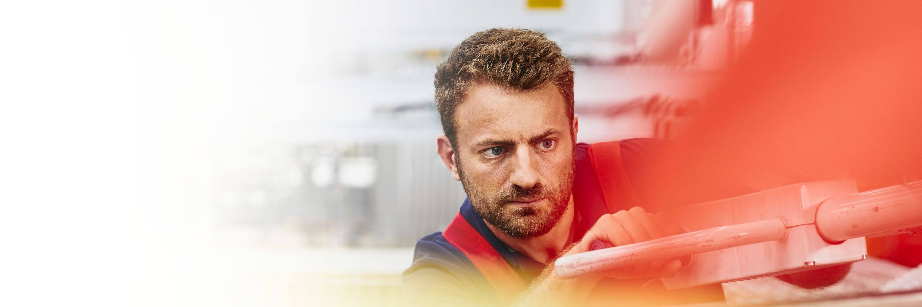 Focused man aligning something/working with a machine in a production site.