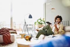 Smiling man sitting on a couch holding a notebook and a pen.