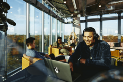 man wearing headphone, smiling in an openspace