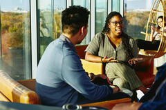 Two people having a conversation while sitting down in a lounge environment.