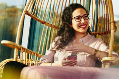 woman smiling, sitting on a rotan chair