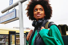 Smiling woman, looking away on train platform. Train in background.