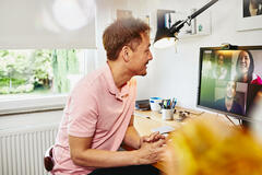 Man sitting at desk in his home office, meeting colleagues in a online meeting.