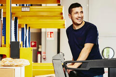 Smiling man standing on a forklift.