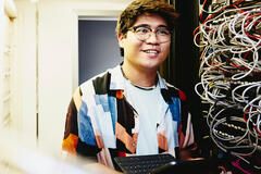 Smiling man holding an tablet standing in a servers room.