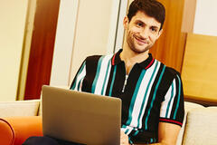 Man sitting on couch working on laptop. 