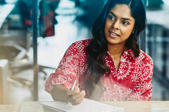 Woman working in an office, sitting at a table making notes.