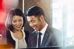 Male and female, smiling and looking down