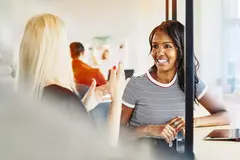 Two female having a conversation. Smiling.
