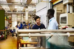 Two colleagues working together on a maleufacturing site.
