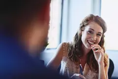 Womale smiling at a colleague holding a pen.Randstad Human Forward