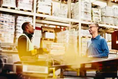Two male working/having a conversation in a warehouse
