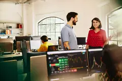 Two colleagues male and female having a chat standing between desks.
