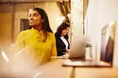 Two smiling female working on their laptop.
