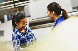 2 femmes souriantes qui parlent sur leur lieu de travail
