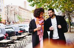 man and woman walking down the street with a coffee to go