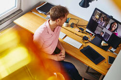 Man setting at his desk in a home office, seen from above. Meeting colleagues in an online meeting.