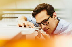 Man wearing glasses adjusting something on a production site