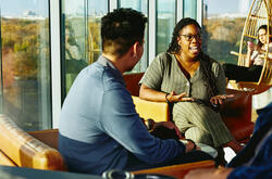 Two people having a conversation while sitting down in a lounge environment.