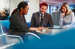 Business man and women having a meeting, smiling and taking notes in an office.