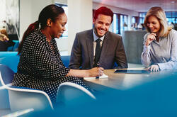 Business man and women having a meeting, smiling and taking notes in an office.