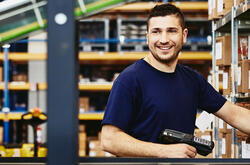 Smiling man standing behind a conveyor belt