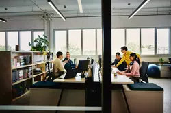 People working at an office setting, sitting behind a computer