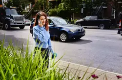 Female, talking on mobile phone, walking on sidewalk in busy street