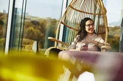 Woman smiling looking away while sitting down and holding her phone.