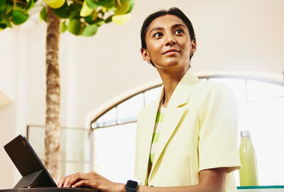 Smiling woman sitting at table working on a tablet.