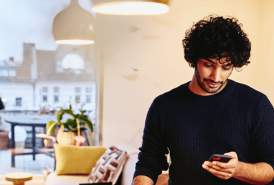 man looking at his cell phone with living room in the background