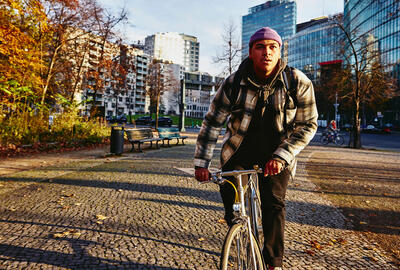 Cycling man, autumn trees and office buildings on the background.