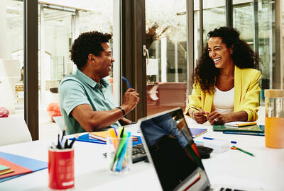 Man and woman having a laugh during a meeting in a meeting room.