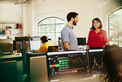 Two colleagues man and woman having a chat standing between desks.