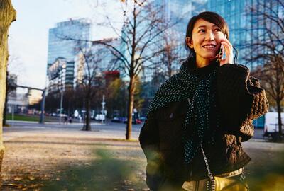 Smiling woman on the phone, office buildings on background.