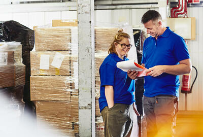 Three people working on an assembly line with packages. Smiling.
