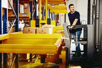 Smiling man standing on a forklift.