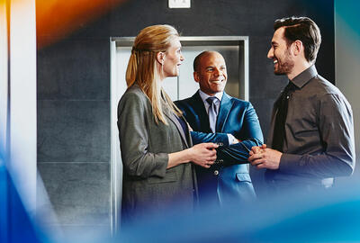 Group of people talking near an elevator.