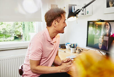 Man sitting at desk in his home office, meeting colleagues in a online meeting.