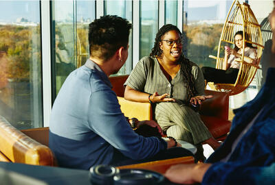 Two people having a conversation while sitting down in a lounge environment.