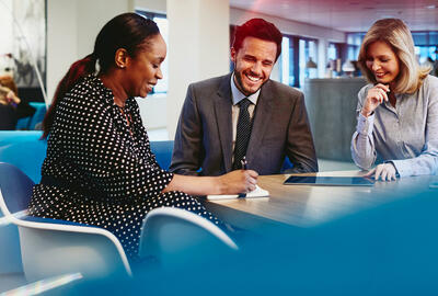 Business man and women having a meeting, smiling and taking notes in an office.