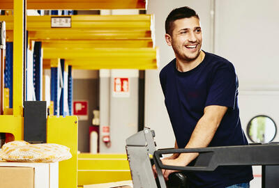 Smiling man standing on a forklift.