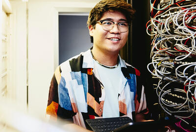 Smiling man holding an tablet standing in a servers room.