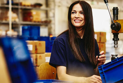 Smiling woman working on a manufacturing site.