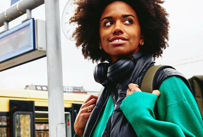 Smiling woman, looking away on train platform. Train in background.