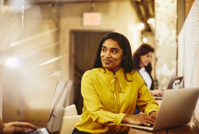 Woman working on her laptop while having a conversation