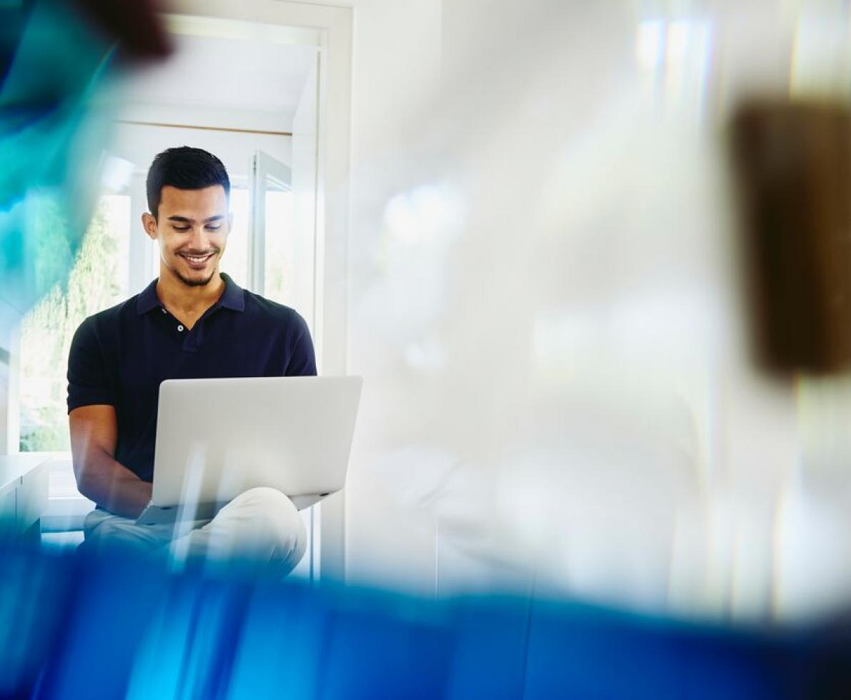 Smiling man working from home on laptop.