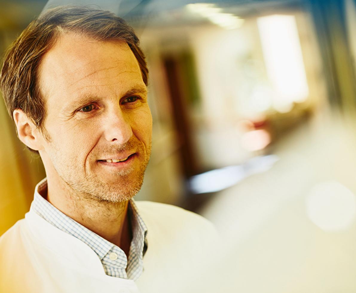 man smiling to the right and wearing a lab coat